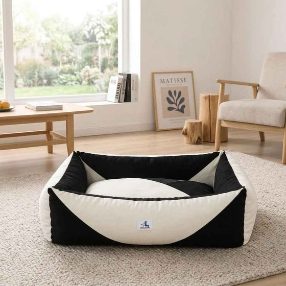 Orthopaedic dog bed with black sides and white pressure-relief bolster in a low oval shape